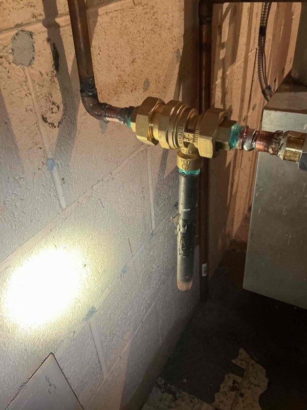 Responded to service call for 22-year-old boiler system located in basement with reported expansion tank concerns. Conducted thorough inspection of hydronic heating system components, including expansion tank, pressure relief valve, and associated copper piping connections. Evaluated brass valve assembly and galvanized steel piping for proper operation and signs of water hammer or pressure irregularities. Inspected copper pipe connections for oxidation, corrosion, and potential leak points at threaded fittings and junction points. Assessed expansion tank for waterlogging, proper air charge, and mounting integrity. Performed comprehensive boiler maintenance including system pressure verification, visual inspection of all plumbing connections, and evaluation of flexible connector hoses for deterioration. Documented condition of all visible components with photographic evidence showing valve configurations, pipe routing, and connection points for future reference and maintenance tracking.