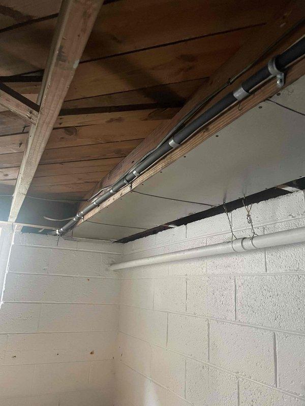 Conducted comprehensive site evaluation for complete air conditioning system replacement at residential property. Assessed existing outdoor AC unit of unknown age and documented current installation configuration. Inspected interior basement/garage area with concrete block walls where HVAC components interface with structure, noting exposed ceiling joists and available mounting points for new equipment. Evaluated exterior utility connections including electrical service panels, gas meter, and existing conduit routing on brick facade. Documented glass block window locations and clearance requirements for equipment access and ventilation. Photographed all relevant areas to determine proper equipment sizing, electrical service capacity, refrigerant line routing options, and condensate drainage requirements. Provided customer with detailed replacement system recommendations and installation specifications.