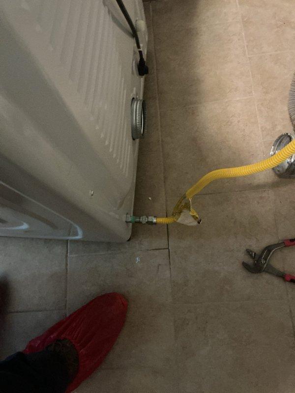 Installed flexible gas line connection to dryer unit, securing all fittings with proper metal clamps and ensuring leak-free operation. Connected yellow corrugated stainless steel tubing from wall outlet to appliance with appropriate shut-off valve and tested system for safety compliance.