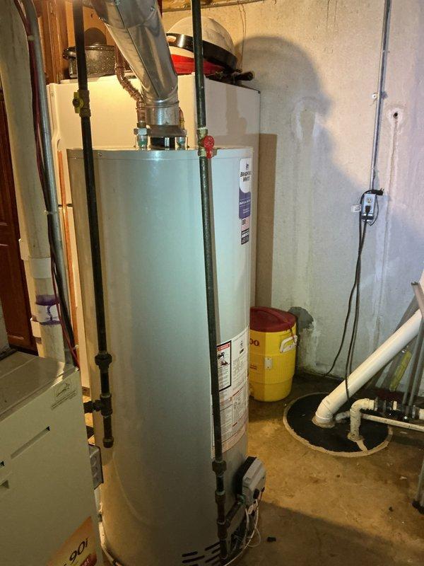 Responded to service call for 13-year-old Bradford White 50-gallon natural gas water heater (Model RG250T6N) experiencing active leaking from top connections and suspected bottom tank failure. Upon inspection in basement utility room, confirmed multiple leak points indicating tank integrity compromise. Due to age of unit (manufactured 2012) and extent of damage, recommended full water heater replacement. Noted that new installation will require addition of drain pan for code compliance, which was not present on existing unit. Documented existing plumbing configuration including copper supply lines, gas connections, and metal vent ducting for replacement specifications.