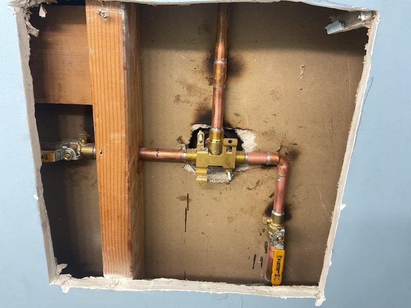 Completed shower valve replacement requiring wall access. Cut access panel in bathroom wall to expose existing plumbing infrastructure and removed failed shower valve assembly. Installed new brass shower valve with copper pipe connections, ensuring proper positioning and secure mounting to wall studs. Soldered all copper joints and tested system for leaks. Verified proper hot and cold water flow and temperature control operation. Left access panel open for customer inspection prior to drywall repair.