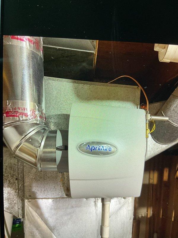 Installed AprilAire whole-home humidifier system integrated with existing HVAC ductwork in basement utility area. Mounted humidifier unit to supply plenum with proper duct connections, installed copper water supply line, and wired AprilAire automatic humidistat control to wall for precise indoor humidity management and optimal comfort control.