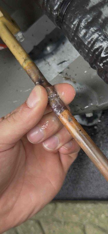 Responded to warranty call for AC unit experiencing short cycling and improper operation. Upon inspection, discovered severe corrosion and deterioration at refrigerant line connection point on outdoor condensing unit. Corroded copper tubing showed moisture accumulation and material breakdown at joint, indicating refrigerant leak causing system to cycle improperly. Documented damaged components with photos showing compromised connection and surrounding refrigerant lines. Accessed service valves and attached manifold gauges to assess system pressures. Unit installed June 2026, located in basement with condensing unit on exterior concrete pad. Corrosion at connection point determined to be manufacturing or installation defect covered under warranty terms. Recommended replacement of affected refrigerant line section and proper brazing of new connection to restore system integrity and resolve cycling issue.