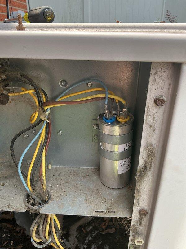 Responded to no cooling complaint on 7-year-old residential air conditioning system located at rear of property. Upon arrival, performed diagnostic testing on outdoor condenser unit using digital multimeter to assess electrical components. Testing revealed failed dual run capacitor showing signs of corrosion, discoloration, and terminal degradation. Capacitor tested outside acceptable microfarad range, preventing compressor and condenser fan motor from operating. Removed defective capacitor from electrical compartment, disconnected wiring from terminals, and installed new replacement capacitor with proper microfarad rating. Secured all electrical connections, verified proper wire routing, and reassembled unit housing. Cycled system through complete startup sequence, confirmed compressor engagement, verified condenser fan operation, and measured proper voltage and amperage at all components. System restored to normal cooling operation with all components functioning within manufacturer 