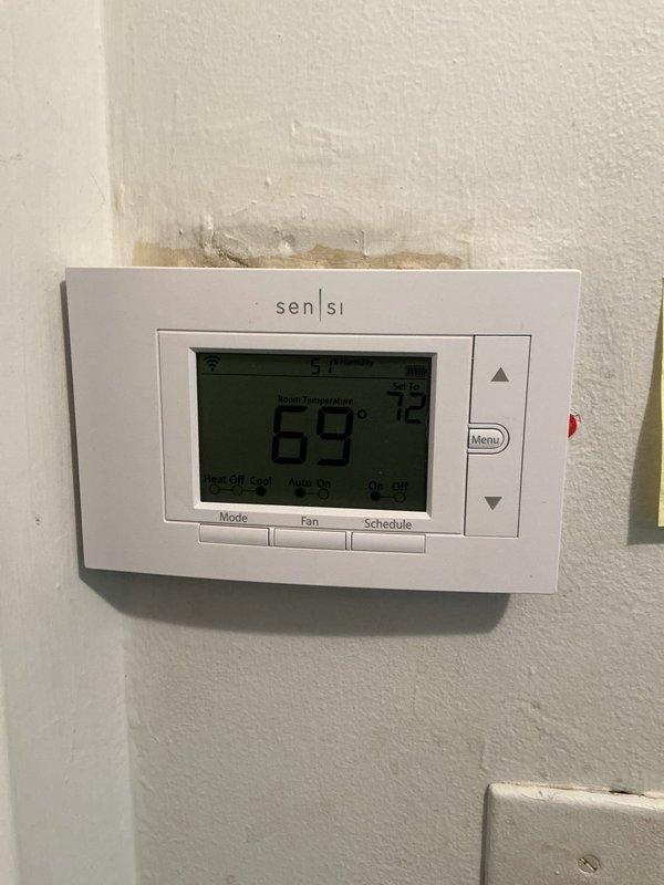 Completed comprehensive Gold AC inspection on 4-year-old Bryant HVAC system with air handler located in basement. Performed full system evaluation including thermostat operation verification (Sensi digital unit displaying 69°F), inspected furnace unit and associated components, checked PVC condensate drainage and venting systems, examined ductwork and plenum connections, and verified proper clearances around equipment. Inspected outdoor condenser unit and advised customer to maintain clear area around condenser free of debris and animal waste. All system components operational and accessible for maintenance. Documentation completed with photographic records of thermostat controls and basement mechanical equipment installation.
