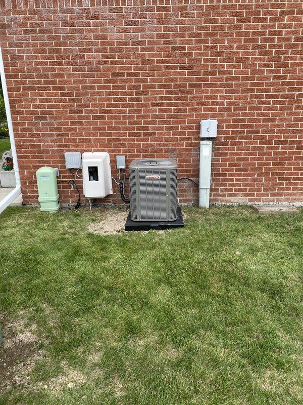 Completed installation of 2-ton Bryant air conditioning system with matching evaporator coil on left side of residence. Mounted condenser unit on composite pad against exterior brick wall, established proper electrical connections via junction boxes, and installed condensate drain line with PVC piping. Indoor air handler positioned in utility room with all refrigerant lines connected, ductwork attached, and system tested for proper operation and reconnection to existing infrastructure.