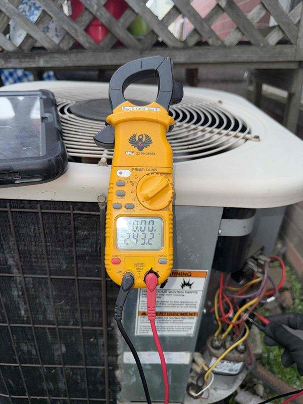 Completed comprehensive Gold AC inspection on 26-year-old outdoor condensing unit. Performed electrical diagnostics using clamp meter to verify amperage draw and system performance. Inspected condenser coils through mesh grille, noting unit's age and weathered exterior condition. Evaluated fan assembly operation and overall system functionality. Unit currently operational with air handler/coil located in basement. Documented equipment condition with photographic evidence showing outdoor condenser positioned on concrete pad with surrounding vegetation growth and minor debris accumulation at base.