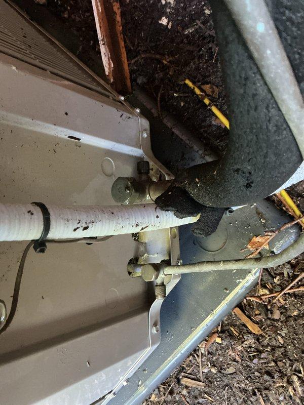 Completed comprehensive Gold AC Inspection and tune-up on 9-year-old air conditioning system with basement-located air handler and exterior condenser unit. Performed full system evaluation including refrigerant level check, electrical component testing, condenser coil inspection and cleaning, blower motor assessment, and thermostat calibration verification. Exterior condenser unit showed normal wear with debris accumulation around base; cleared organic matter and wood chips from perimeter to ensure proper airflow and drainage. Inspected refrigerant lines and PVC condensate drain; all connections secure with no visible leaks detected. System operating within manufacturer specifications with adequate cooling capacity and proper cycling. Documented heavy rust and corrosion observed on water heater top connections during visual inspection of mechanical room, though this falls outside scope of AC maintenance service. All AC system components functioning properly with no immediate repairs re
