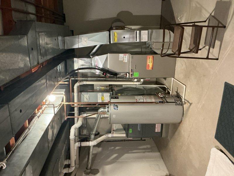 Completed comprehensive Gold AC inspection on multi-unit residential system consisting of two air conditioning units and one generator, all ranging from 3-10+ years in age. Performed thorough evaluation of basement-located mini split, air handler, and evaporator coil assemblies. Inspected mechanical room housing gray metal cabinet-style HVAC equipment, verifying proper clearances and accessibility for future maintenance. Examined all refrigerant line sets, copper piping connections, and soldered joints for signs of wear or potential leaks. Assessed white PVC condensate drainage system with multiple bends and connections, confirming proper pitch and flow. Verified blue valve operation on copper refrigerant lines and inspected flexible silver ventilation ductwork for proper sealing and support. Evaluated electrical connections, mounting hardware, and safety controls on all units. Checked metal rectangular duct system for proper sealing at seams and joints. Confirmed all equipment operati