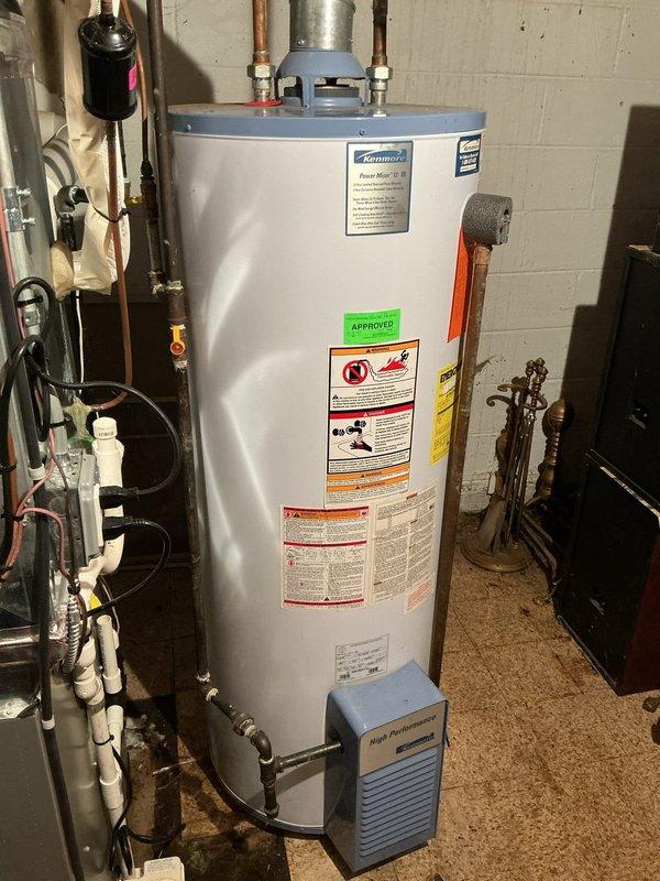 Responded to reported water leak suspected to originate from water heater in basement utility area. Upon inspection, examined Kenmore water heater unit and surrounding plumbing connections, including copper supply lines, pressure relief valve, and associated pipe fittings at top of tank. Assessed all visible connections, valves, and tank exterior for signs of active leakage or moisture accumulation. Documented existing plumbing configuration including PVC drainage lines, galvanized ductwork, and expansion tank installation. Verified proper operation of water heater components and identified source of reported leak condition.