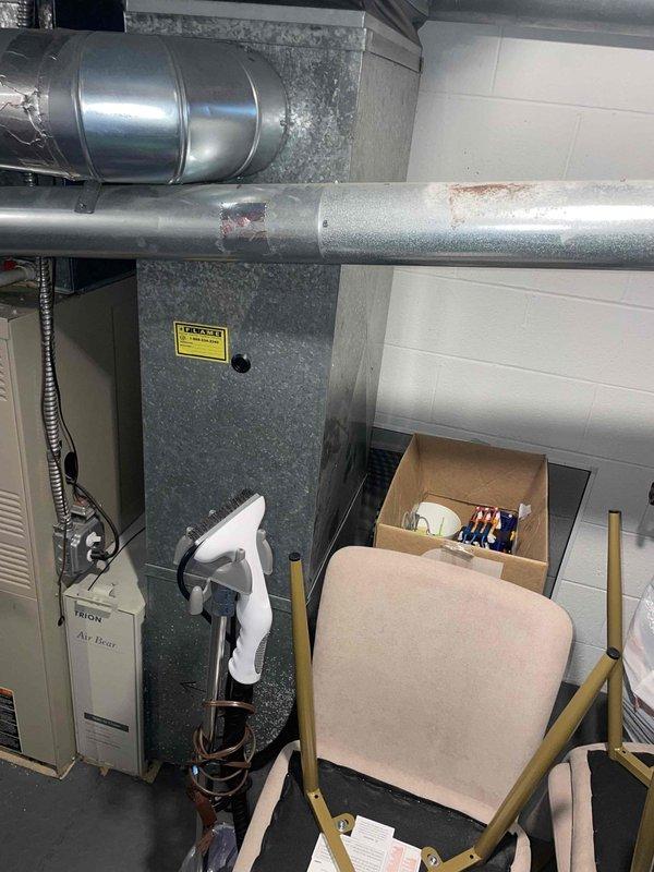 Completed full system estimate on 27-year-old Lennox HVAC system following annual AC tune-up and cooling maintenance inspection. System confirmed operational upon arrival. Evaluated complete installation including gray metal air handler unit, metallic ductwork with flexible corrugated sections, and beige Teton Air Bear filtration component located in basement utility area. Assessed condition of existing equipment showing age-related wear including minor surface oxidation on horizontal ductwork and visible rust spots on metallic surfaces. Documented current system configuration with white concrete block walls and concrete flooring typical of mechanical room installations. Provided comprehensive estimate options for full system replacement considering equipment age and observed wear patterns on existing components.