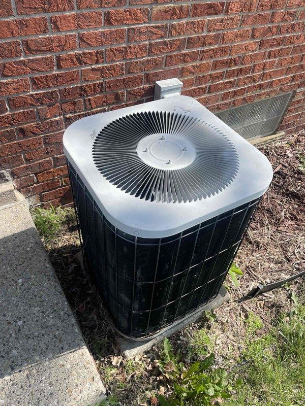 Provided comprehensive estimate for complete central air conditioning system replacement at owner-occupied residence. Existing outdoor condenser unit, approximately 20 years old and located in backyard against brick exterior wall, has reached end of serviceable life. Unit assessed and documented with photographic records showing round-top condenser with radial fin pattern positioned on concrete pad with electrical disconnect box mounted on wall above. Presented replacement options for new energy-efficient central AC system to restore reliable cooling capacity.