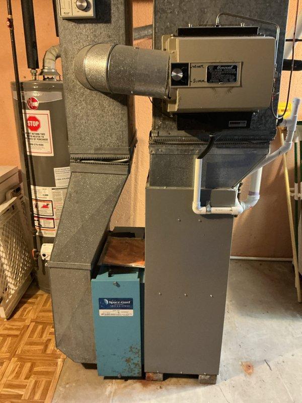 Responded to service call for central air conditioning system not cooling. Upon inspection, discovered cracked heat exchanger in furnace unit located in basement utility area. Evaluated complete HVAC system including 10-year-old outdoor AC unit installed in 2018. Documented equipment condition through photography showing furnace with cylindrical blower housing, Aqua-Gard water treatment component, and associated ductwork. Provided comprehensive estimate for full system replacement due to failed heat exchanger and aging air conditioning equipment.
