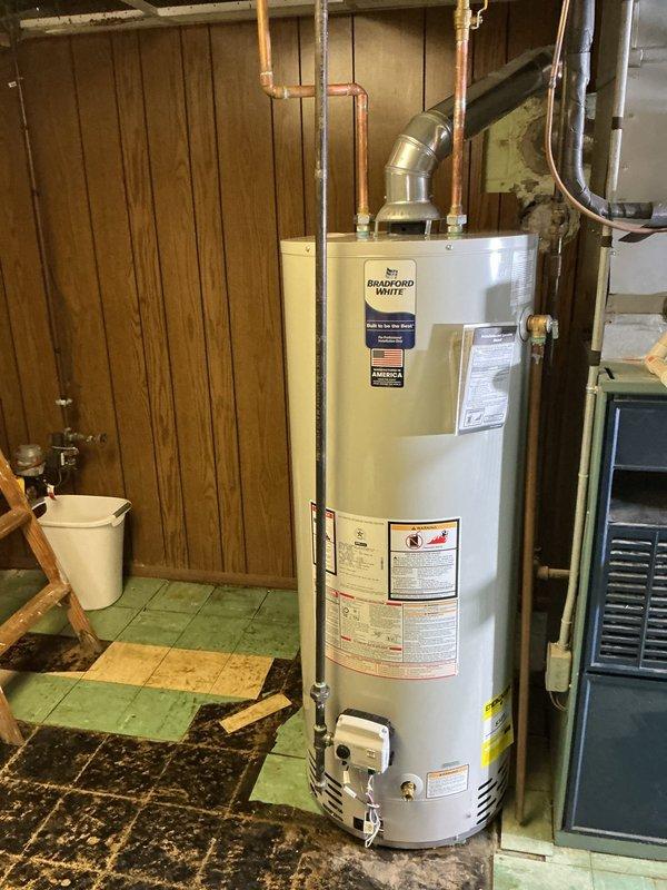 Responded to service call for leaking residential water heater in basement utility area. Upon inspection, confirmed Bradford White tanked water heater was leaking from bottom of unit, indicating internal tank failure. Disconnected existing water supply lines, drain valve, and gas connections. Removed failed unit and installed new Bradford White residential gas-fired water heater. Connected copper supply piping, installed code-compliant temperature and pressure relief valve with proper discharge piping, and reconnected gas line with new flexible connector. Attached vent pipe to existing exhaust system, verified proper draft, and tested all connections for leaks. Filled tank, purged air from system, lit pilot light, and verified proper burner operation and temperature settings. Conducted final inspection of all plumbing connections and gas fittings to ensure leak-free installation. Unit tested and operating within manufacturer specifications upon completion.