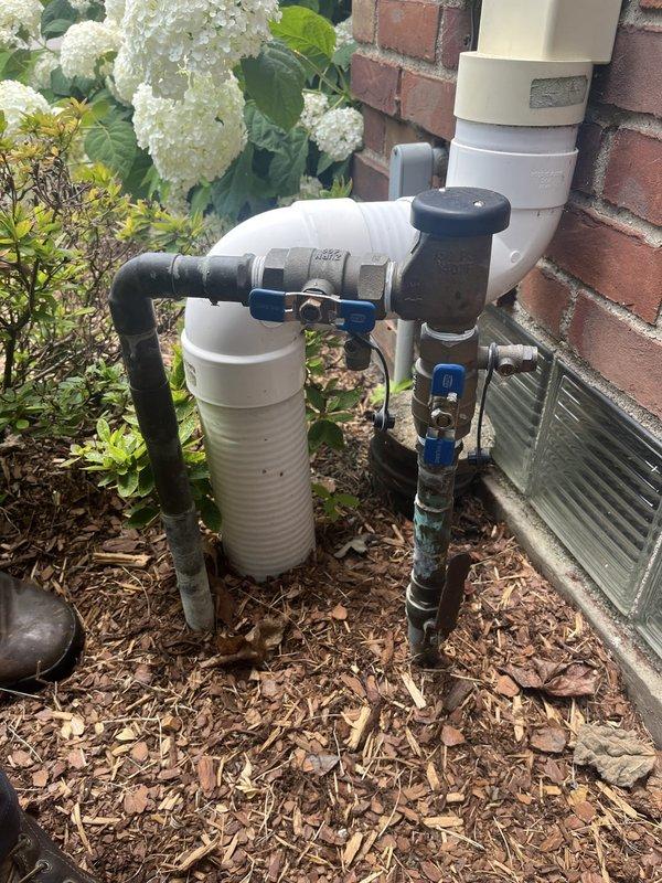 Completed backflow prevention device testing on residential outdoor plumbing assembly located against exterior brick wall. Inspected multi-valve configuration including ball valves, pressure regulator, and associated piping connections. Removed and examined test cocks with rubber seals to verify proper operation and compliance with municipal requirements, documenting equipment condition through photography for certification records.