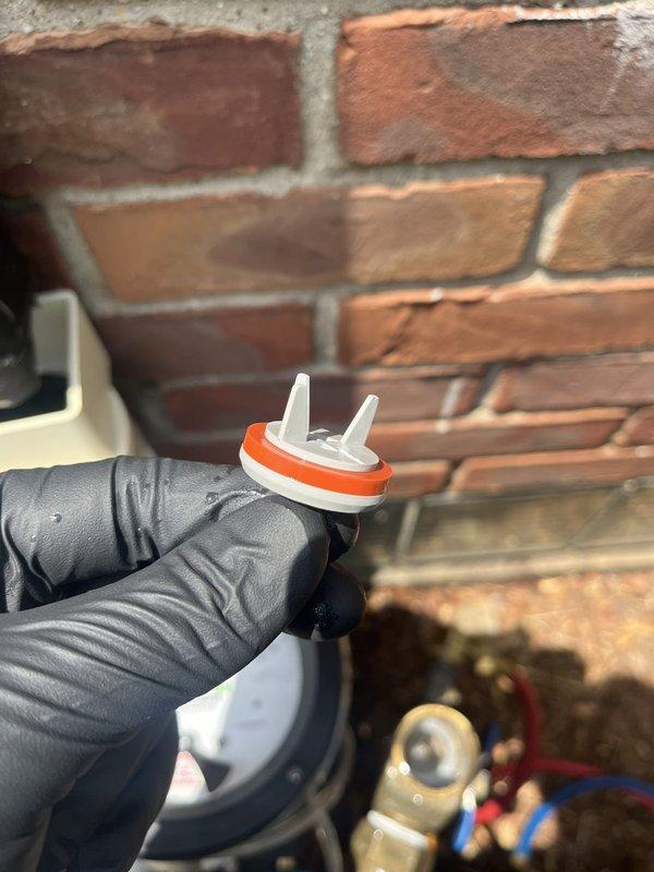 Completed backflow prevention device testing on residential outdoor plumbing assembly located against exterior brick wall. Inspected multi-valve configuration including ball valves, pressure regulator, and associated piping connections. Removed and examined test cocks with rubber seals to verify proper operation and compliance with municipal requirements, documenting equipment condition through photography for certification records.