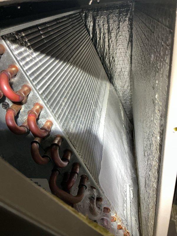 Completed comprehensive Gold AC inspection on 14-year-old air conditioning system with air handler located in basement. Performed thorough examination of evaporator coil assembly, verifying proper refrigerant line connections and coil condition. Inspected aluminum fin surfaces, copper refrigerant tubing, and U-bend connections for signs of deterioration, leaks, or damage. Documented equipment condition through photographic records showing evaporator coil with parallel aluminum fins, multiple copper refrigerant lines, and insulated ductwork connections. Verified all refrigerant lines showed expected patina consistent with equipment age. Confirmed air handler cabinet and coil assembly components are properly secured and functioning. System operational at time of inspection with no immediate service concerns identified.