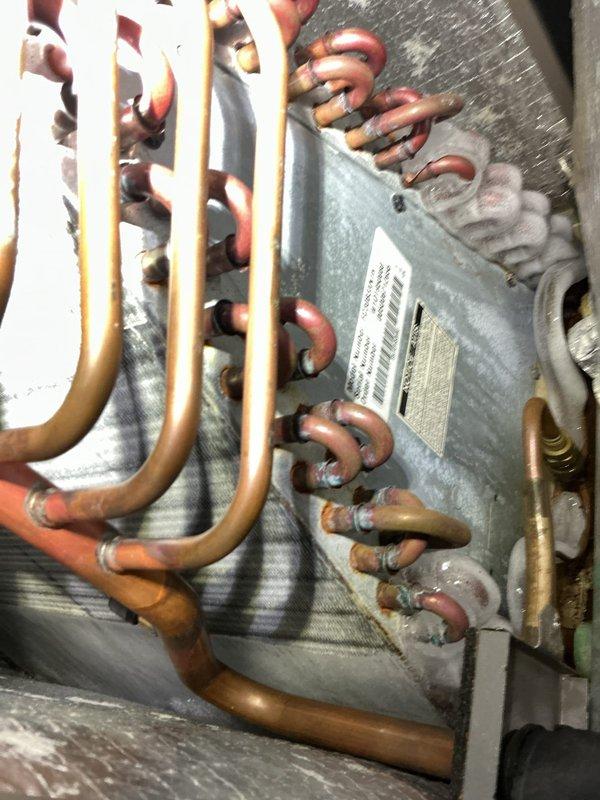 Completed comprehensive Gold AC inspection on 14-year-old air conditioning system with air handler located in basement. Performed thorough examination of evaporator coil assembly, verifying proper refrigerant line connections and coil condition. Inspected aluminum fin surfaces, copper refrigerant tubing, and U-bend connections for signs of deterioration, leaks, or damage. Documented equipment condition through photographic records showing evaporator coil with parallel aluminum fins, multiple copper refrigerant lines, and insulated ductwork connections. Verified all refrigerant lines showed expected patina consistent with equipment age. Confirmed air handler cabinet and coil assembly components are properly secured and functioning. System operational at time of inspection with no immediate service concerns identified.