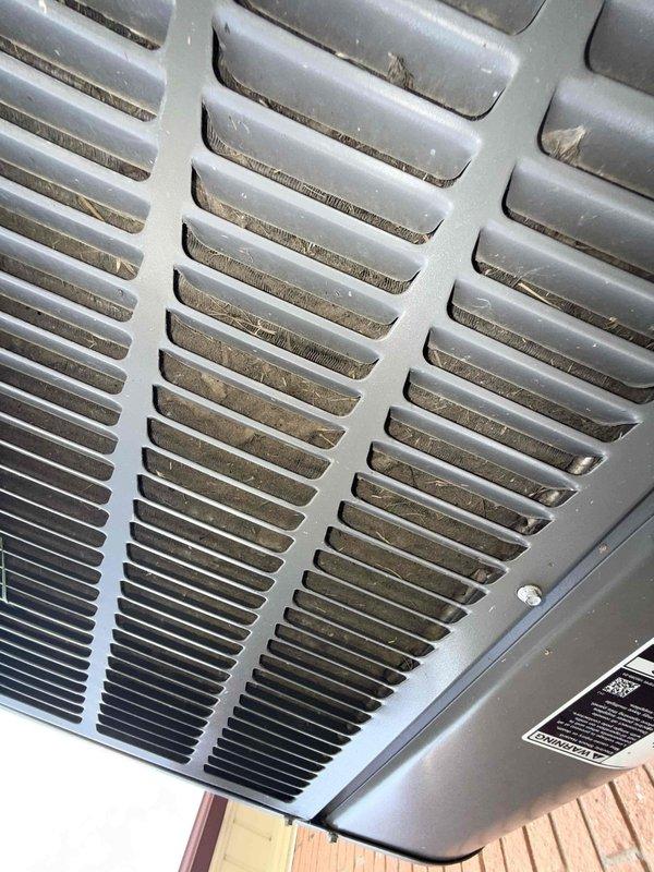 Responded to service call for air conditioning system blowing warm air. Unit located in rear of residence with evaporator coil installed at furnace. Upon inspection, observed significant dust and debris accumulation on outdoor condenser unit fins and ventilation components, which restricts proper airflow and reduces heat transfer efficiency. Documented current condition of equipment and exterior utility line connections for service records.