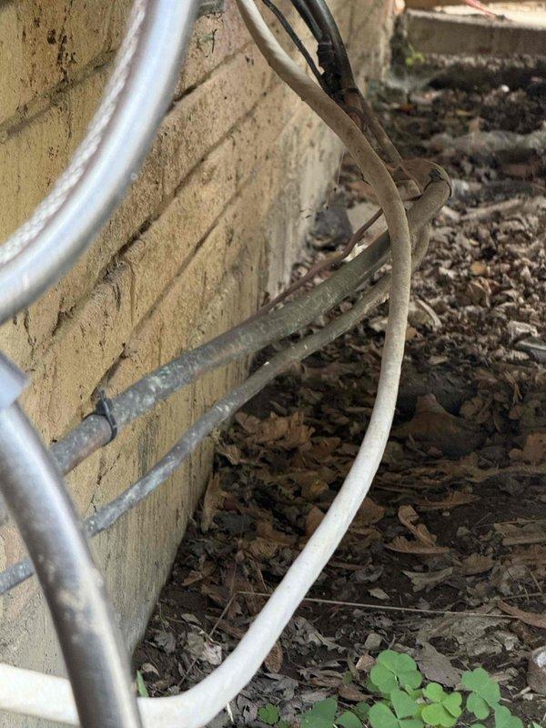 Responded to service call for air conditioning system blowing warm air. Unit located in rear of residence with evaporator coil installed at furnace. Upon inspection, observed significant dust and debris accumulation on outdoor condenser unit fins and ventilation components, which restricts proper airflow and reduces heat transfer efficiency. Documented current condition of equipment and exterior utility line connections for service records.