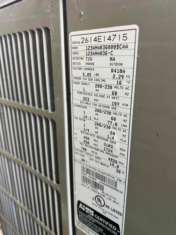 Completed comprehensive Gold AC inspection on 10+ year old residential air conditioning system with basement-located air handler. Performed detailed evaluation of 123ANA036-C unit (S/N 2614E14715), a 3-ton R410A system rated at 208-230V. Conducted electrical diagnostics using digital multimeter to verify proper voltage and amperage readings, confirming system operating within manufacturer specifications. Inspected condenser unit exterior condition, verified nameplate data legibility, and documented equipment specifications. Unit currently operational with no immediate concerns identified. Captured photographic documentation of equipment nameplate and diagnostic measurements for service records.