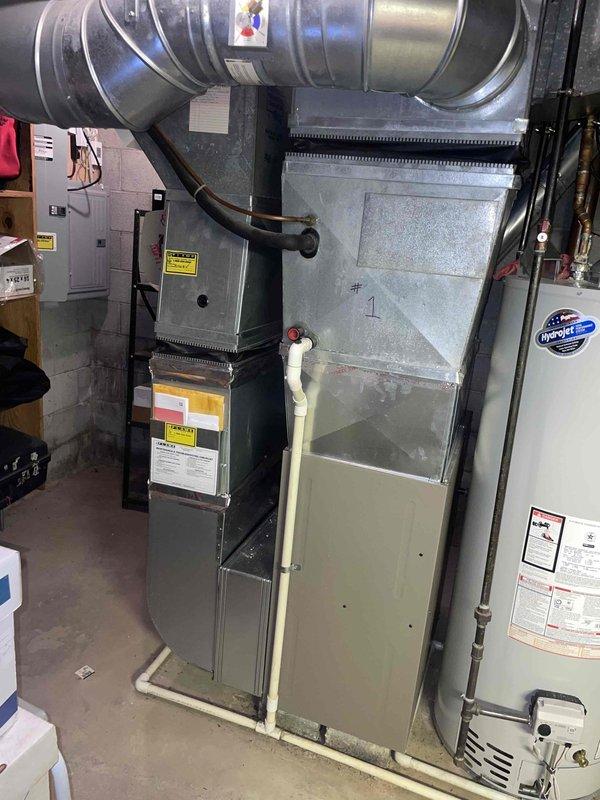 Completed comprehensive HVAC system evaluation for residential property with 10+ year old R22 equipment experiencing low refrigerant charge. Inspected basement-mounted vertical furnace with connected air handler, ductwork, and electrical components, as well as attic-installed evaporator coil with associated refrigerant lines and control systems. Documented existing system configuration including galvanized metal ductwork, flexible duct connections, copper refrigerant piping, electrical panels, and drainage components to provide detailed replacement estimate for outdated R22 system.
