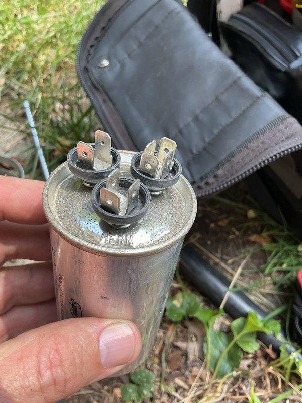 Responded to no cooling call on residential air conditioning system. Upon inspection, found failed dual-run capacitor with visible terminal discoloration and tarnishing, preventing compressor and condenser fan motor operation. Replaced defective capacitor with new unit matching proper microfarad and voltage specifications. Additionally observed heavily soiled condenser coil with significant dirt and debris accumulation restricting airflow through fins. System restored to normal cooling operation and tested for proper function.