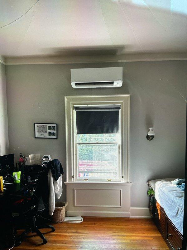 Completed full mini split heat pump system installation in rear yard area, including both interior and exterior components. Mounted Daikin wall unit above bedroom window with proper clearances and installed matching outdoor condenser unit on elevated platform with vibration-dampening feet against building exterior. Ran new dedicated electrical circuit, installed refrigerant line sets with PVC line cover, routed condensate drainage, pulled mechanical and electrical permits, tested system operation, and verified proper heating and cooling functionality upon completion.