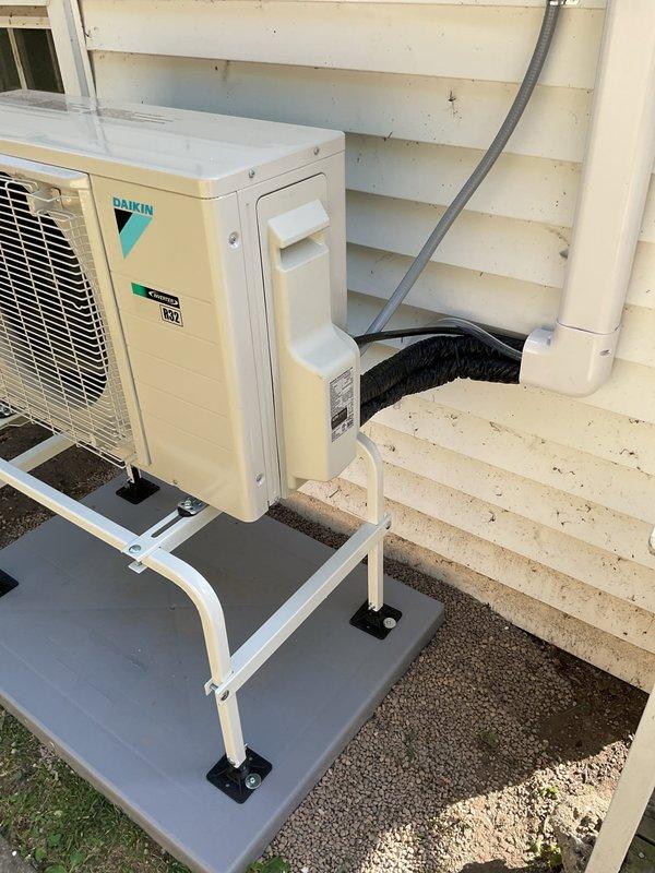 Completed full mini split heat pump system installation in rear yard area, including both interior and exterior components. Mounted Daikin wall unit above bedroom window with proper clearances and installed matching outdoor condenser unit on elevated platform with vibration-dampening feet against building exterior. Ran new dedicated electrical circuit, installed refrigerant line sets with PVC line cover, routed condensate drainage, pulled mechanical and electrical permits, tested system operation, and verified proper heating and cooling functionality upon completion.