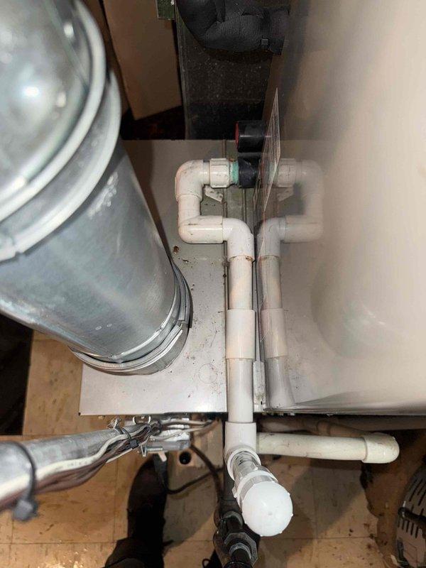 Responded to water leak complaint originating from furnace area in basement. Upon inspection, identified failed condensate pump as source of water discharge, not the adjacent water heater as initially suspected. The 20+ year old furnace's air conditioning system was actively producing condensate, which the malfunctioning pump was unable to properly evacuate, resulting in water overflow onto basement floor near laundry area. Documented existing conditions including corroded copper piping, aging PVC condensate drainage system, and condensate pump unit positioning. Photographed mechanical room layout, pump installation, and associated plumbing connections for service records. Air conditioning system remained operational during inspection.