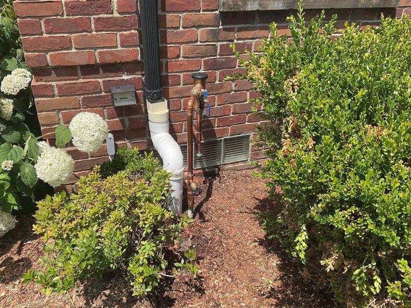 Completed installation of PVB (Pressure Vacuum Breaker) backflow prevention device on exterior residential water supply line. Integrated new backflow preventer assembly with existing copper piping system, utilizing proper PVC connections and shut-off valves for code compliance. Installation mounted securely to brick exterior wall with appropriate clearances for testing and maintenance access, positioned above grade level in landscaped area to prevent submersion and ensure proper drainage.