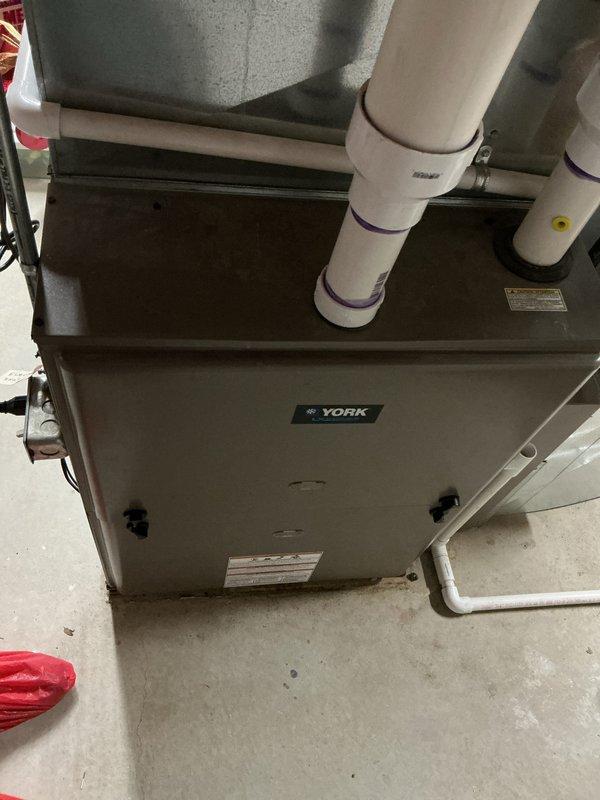 Provided comprehensive replacement estimate for both air conditioning and furnace systems in basement installation. Current 10+ year old York air handler unit is non-operational. Evaluated existing natural gas furnace configuration, ductwork connections, refrigerant lines, and condensate drainage system with white PVC piping. Documented equipment specifications and installation requirements for complete HVAC system replacement.