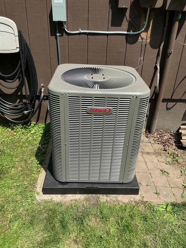 Completed installation of 3-ton Lennox air conditioning system with matching evaporator coil in rear yard location. Unit was positioned on concrete pad against building exterior, with electrical disconnect box mounted on wall and proper conduit connections established. All mechanical, electrical, and AC permits were requested and system was reconnected to existing infrastructure per code requirements.