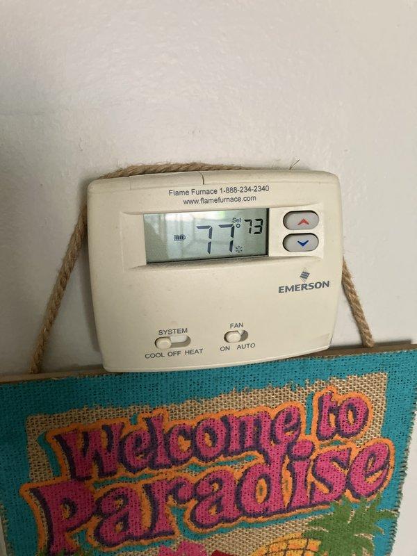 Responded to service call for 10-year-old Lennox air conditioning system that had stopped cooling properly. Upon inspection, diagnosed R22 refrigerant system with low charge. Verified thermostat operation showing current temperature of 77 degrees with setpoint at 73 degrees. Assessed outdoor condenser unit positioned against exterior brick wall and determined system age and refrigerant type made repair cost-prohibitive. Provided estimate for complete HVAC system replacement due to obsolete R22 refrigerant, system age, and declining efficiency.