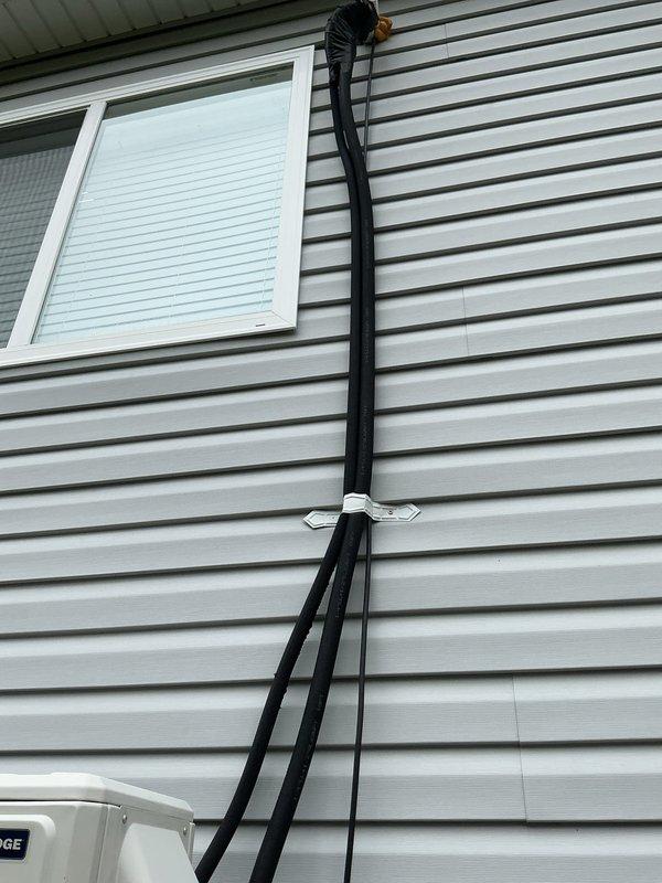 Performed service call on 3-year-old Blueridge mini split system located in garage/ADU. Upon arrival, conducted thorough inspection of outdoor condensing unit and refrigerant line set installation. System was operational with cooling capacity intact and no reported loss of function. Visually inspected condenser unit mounted on exterior wooden platform, verifying secure mounting and proper clearances. Examined refrigerant line set routing along building exterior, checking insulation integrity and mounting bracket security. Inspected condensate drain line installation including PVC routing and termination point. Verified electrical conduit connections and proper strain relief at unit. No immediate mechanical or refrigerant issues identified during inspection. System operating within normal parameters at time of service.