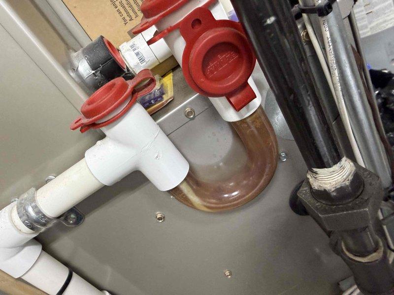 Responded to service call for outdoor air conditioning condenser unit reporting slight operational noise. Inspected condenser unit located on exterior concrete pad, verified unit operation and assessed mechanical components for abnormal sounds. Examined condenser fan motor, compressor, and associated hardware for loose components or wear indicators. Documented equipment condition with photos showing outdoor condenser unit and indoor furnace plumbing connections in main level laundry room. Unit operational at time of inspection with age-related wear consistent with equipment over 10 years old.