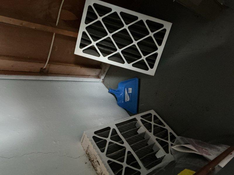 Responded to complaint of uneven cooling throughout residence, with living room and basement overcooling while other rooms received insufficient airflow. Inspected aging HVAC system in basement location and identified heavily soiled air filters restricting airflow and causing poor air distribution. Documented filter condition showing significant dust accumulation and discoloration. Examined ductwork system and noted potential airflow balance issues contributing to inconsistent temperature control between zones. Recommended filter replacement and system balancing to restore proper air distribution throughout all living spaces.