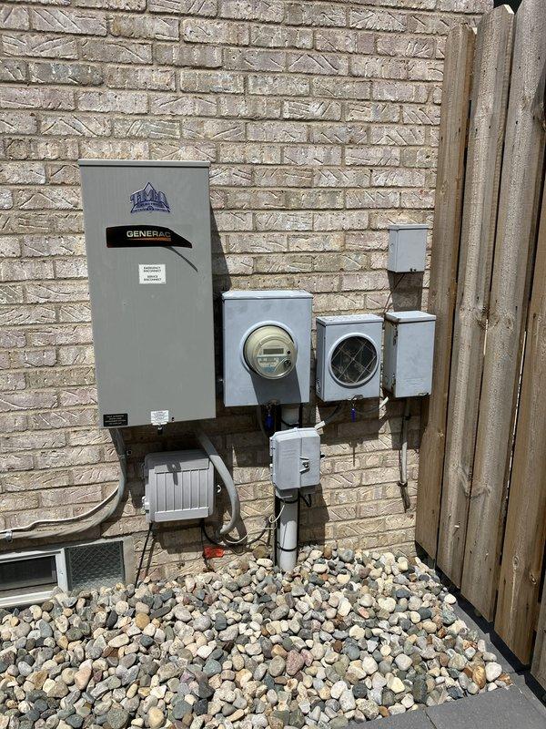 Conducted comprehensive site evaluation for high-efficiency HVAC system replacement. Assessed existing outdoor condenser unit with circular radial ventilation pattern, documented current electrical infrastructure including multiple meter housings and junction boxes mounted on exterior brick wall, and photographed refrigerant line routing and electrical disconnect components. Evaluated equipment placement, existing river rock landscaping base, and electrical service configuration to develop full system replacement estimate specifications.