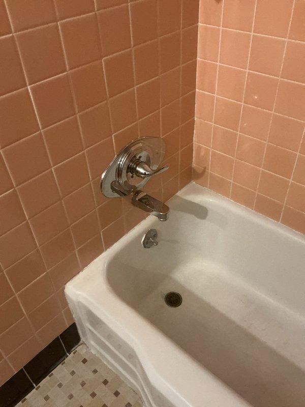Responded to plumbing service call for bathtub faucet replacement. Accessed existing plumbing infrastructure through attic crawl space above bathroom. Removed dated chrome tub spout and faucet assembly from peach-tiled bathroom wall. Installed new PVC supply lines with brass shut-off valves in attic space to provide proper water control and meet current code requirements. Connected new fixtures to updated supply lines, ensuring proper water flow and pressure. Tested installation for leaks and verified proper drainage through existing tub drain assembly. All connections secured and system restored to full operation.
