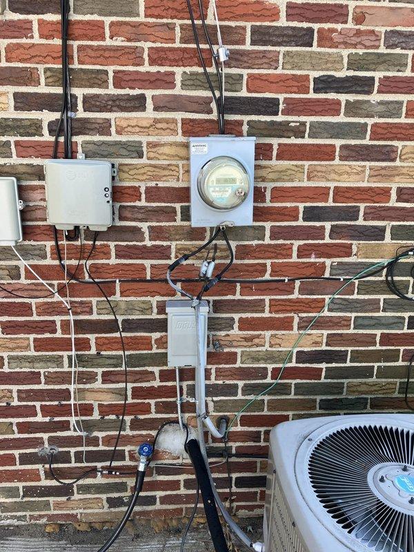 Conducted comprehensive site evaluation for replacement estimate of 15-year-old residential air conditioning system located in backyard. Assessed existing condensing unit positioned on concrete pad against brick exterior wall, documented current equipment condition including condenser coil integrity and cabinet weathering, evaluated electrical service infrastructure including meter location and existing conduit routing, and photographed installation area to develop accurate replacement specifications for owner-occupied property.