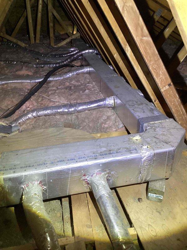 Responded to service call for 20-year-old R22 air conditioning system not cooling adequately, with unit located beside garage. Upon inspection, found system was empty of refrigerant. Assessed existing ductwork system in attic space, including metal supply plenum and flexible duct runs with reflective insulation showing age-related wear. Due to depleted R22 refrigerant, age of equipment, and obsolete refrigerant type, provided comprehensive estimate for complete HVAC system replacement.