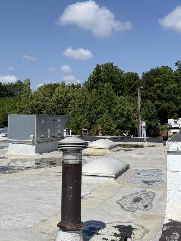 Responded to a no cooling complaint at a commercial facility with rooftop AC units. Upon inspection, found a failed capacitor with severe corrosion on terminals and electrical connections, indicating age-related deterioration. Identified additional maintenance needs including a missing 4L420 belt and four 16x16x2 air filters requiring replacement. Documented equipment conditions with photographs showing weathered rooftop installation and degraded electrical components. Recommended further diagnosis to assess complete system functionality and determine extent of repairs needed for both potentially affected units. Equipment located with furnaces on ground floor and condensing units on accessible rooftop.