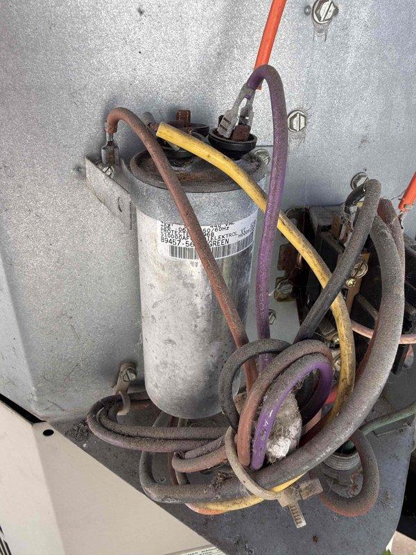 Responded to a no cooling complaint at a commercial facility with rooftop AC units. Upon inspection, found a failed capacitor with severe corrosion on terminals and electrical connections, indicating age-related deterioration. Identified additional maintenance needs including a missing 4L420 belt and four 16x16x2 air filters requiring replacement. Documented equipment conditions with photographs showing weathered rooftop installation and degraded electrical components. Recommended further diagnosis to assess complete system functionality and determine extent of repairs needed for both potentially affected units. Equipment located with furnaces on ground floor and condensing units on accessible rooftop.