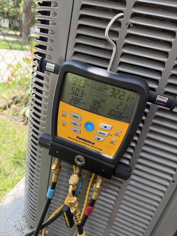 Responded to no cooling complaint on 4-year-old residential AC system with freezing coil condition. Upon arrival, performed comprehensive diagnostic evaluation of outdoor condensing unit and connected refrigerant monitoring equipment to assess system pressures and temperatures. Digital gauge readings revealed abnormal operating parameters consistent with restricted airflow or low refrigerant charge causing evaporator coil icing. Inspected outdoor unit for proper operation, verified electrical connections, and assessed refrigerant line insulation integrity. Documented equipment condition through photographic evidence showing unit placement in basement with outdoor condenser positioned in residential backyard setting. System requires further evaluation of indoor evaporator coil, airflow restrictions, and potential refrigerant leak to resolve freezing issue and restore proper cooling operation.