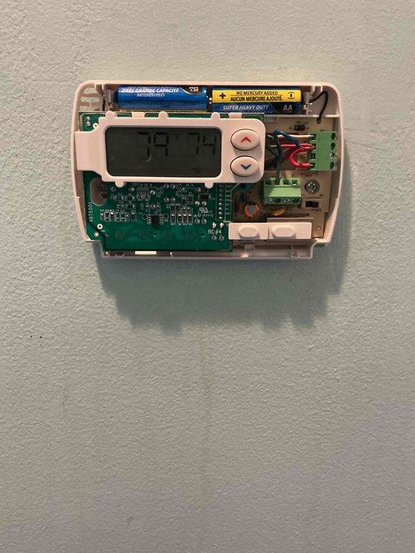 Responded to no cooling complaint on 3-year-old split system with indoor air handler in basement and outdoor condenser unit in backyard. Customer reported indoor fan operational but no cooling despite changing filter and clearing condensate line. Upon arrival, verified thermostat display showing 75.7°F and inspected thermostat wiring connections and battery installation. Examined outdoor condenser unit, noting fan grille and internal components accessible for inspection. Performed diagnostic evaluation of both indoor and outdoor equipment to identify cause of cooling failure on relatively new system.