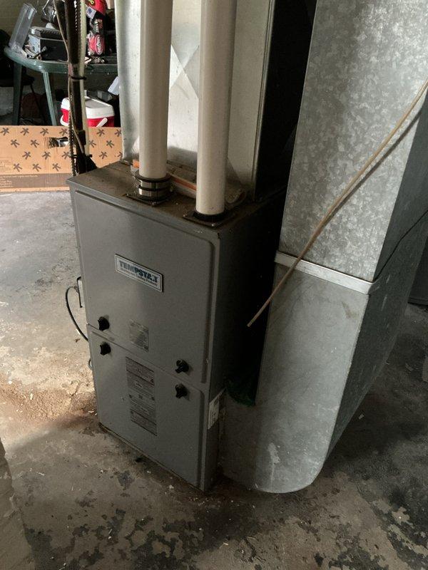 Conducted site evaluation for new air conditioning system installation at property with no existing outdoor AC unit. Assessed proposed exterior installation location and evaluated existing indoor HVAC infrastructure, including furnace and ductwork configuration in basement mechanical room. Documented current system setup and structural considerations for proper outdoor condenser placement and refrigerant line routing. Photographed existing equipment and installation area to develop comprehensive estimate for complete AC system installation including outdoor condensing unit, refrigerant lines, electrical connections, and integration with existing air handler or furnace for cooling distribution.