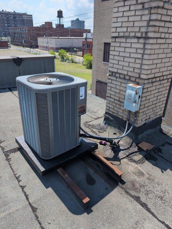 Completed commercial HVAC system replacement involving rooftop condenser installation and first-floor air handler changeout. Accessed roof via second-floor restroom, hoisted equipment to rooftop, and removed existing Lennox upflow air handler. Installed new upflow unit positioned 8" lower than original, requiring custom sheet metal collar fabrication to accommodate height differential. Set new Lennox condenser on rooftop mounting pad with proper support blocking, flushed existing refrigerant line set to ensure system cleanliness, and connected all refrigerant lines. Retained existing thermostat and electrical disconnect per customer request. Verified all electrical connections, tested system operation, and confirmed proper airflow and refrigerant charge levels.