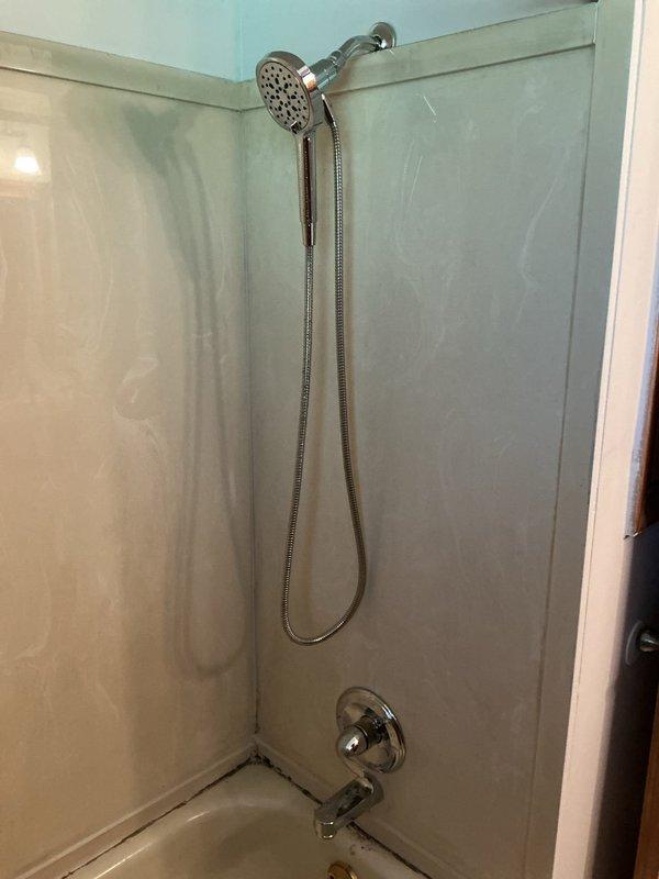 Responded to a broken faucet located behind the wall near the ceiling in a 50-year-old residence. Performed wall access by cutting drywall to expose the concealed plumbing system, revealing copper hot and cold water supply lines with shut-off valves and PVC drainage piping. Repaired the compromised faucet assembly, verified proper water flow and pressure at the tub-shower fixtures, and confirmed all connections were secure with no active leaks.