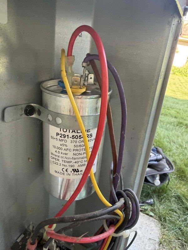 Responded to service call for non-operational air conditioning unit located at rear of property. Upon inspection, diagnosed failed dual-run capacitor (50+5 MFD, 370V) preventing compressor and condenser fan motor operation. Removed defective P291-5054 RS capacitor and installed replacement unit with proper specifications. Verified all electrical connections, tested system operation with clamp meter, and confirmed proper startup and run amperage. Unit restored to full operational status.