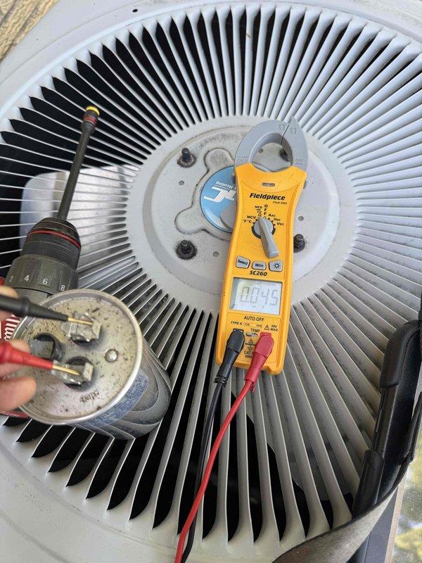 Responded to service call for non-operational air conditioning unit located at rear of property. Upon inspection, diagnosed failed dual-run capacitor (50+5 MFD, 370V) preventing compressor and condenser fan motor operation. Removed defective P291-5054 RS capacitor and installed replacement unit with proper specifications. Verified all electrical connections, tested system operation with clamp meter, and confirmed proper startup and run amperage. Unit restored to full operational status.